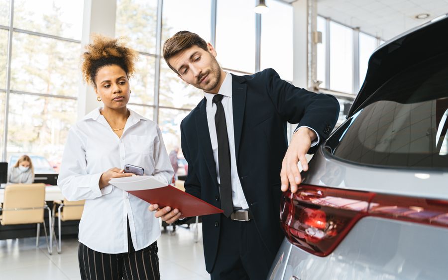 Un vendedor de una agencia mostrándole un auto a una clienta